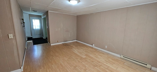 spare room with light wood-type flooring, baseboard heating, and a paneled ceiling