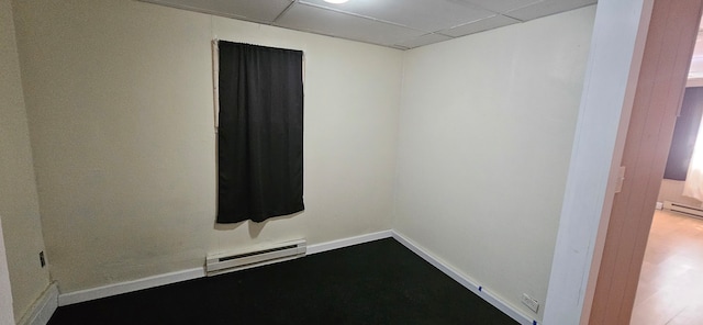 spare room with a paneled ceiling and a baseboard heating unit