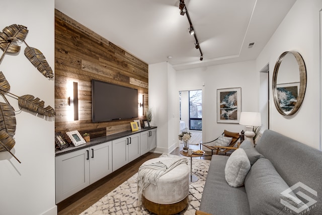 living room featuring track lighting, wood walls, and dark hardwood / wood-style flooring