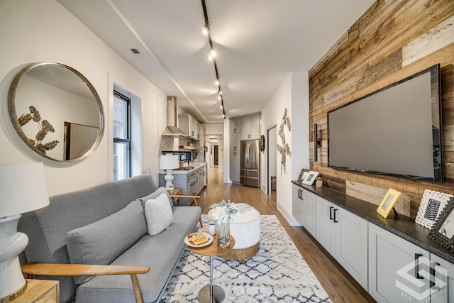 living room featuring rail lighting, wooden walls, and dark hardwood / wood-style flooring