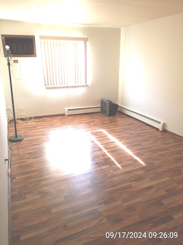 unfurnished room featuring a wall mounted air conditioner, dark wood-type flooring, and a baseboard heating unit