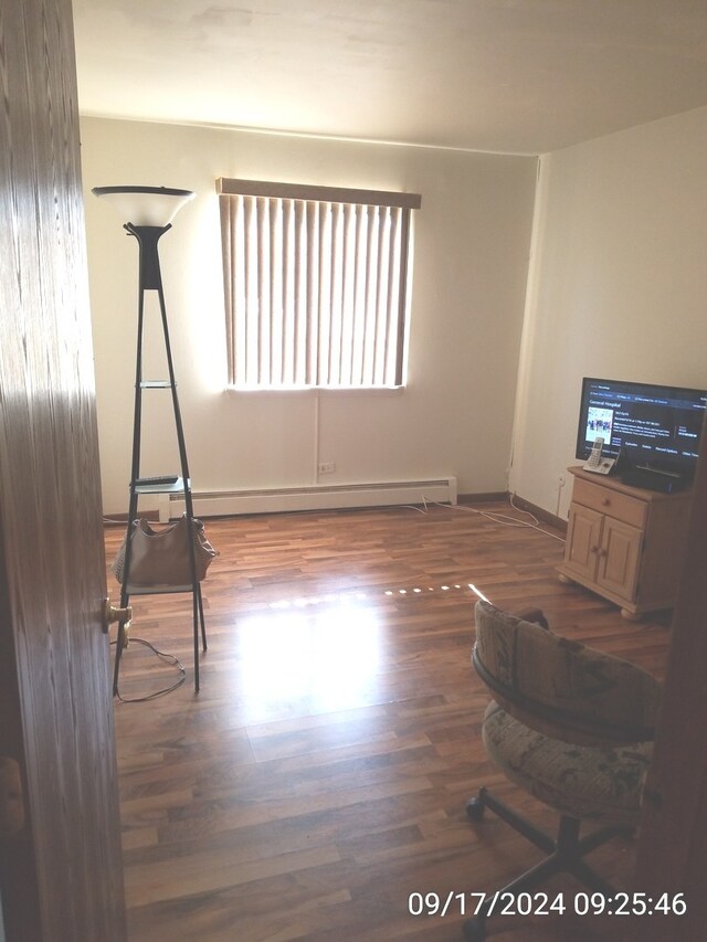 miscellaneous room with a baseboard heating unit and dark hardwood / wood-style floors