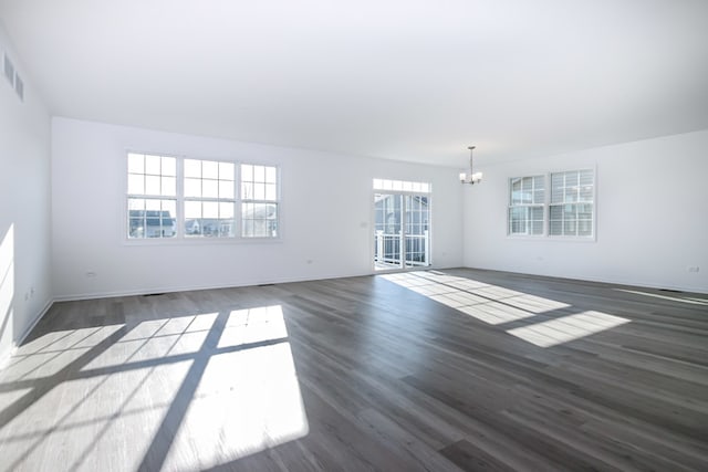 unfurnished living room with dark hardwood / wood-style flooring and an inviting chandelier