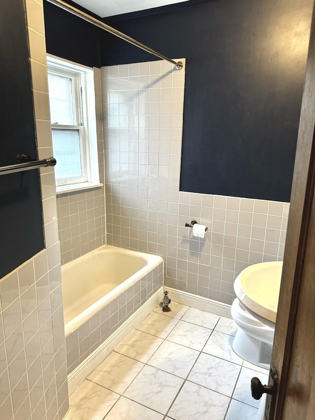 full bath with washtub / shower combination, marble finish floor, toilet, and tile walls