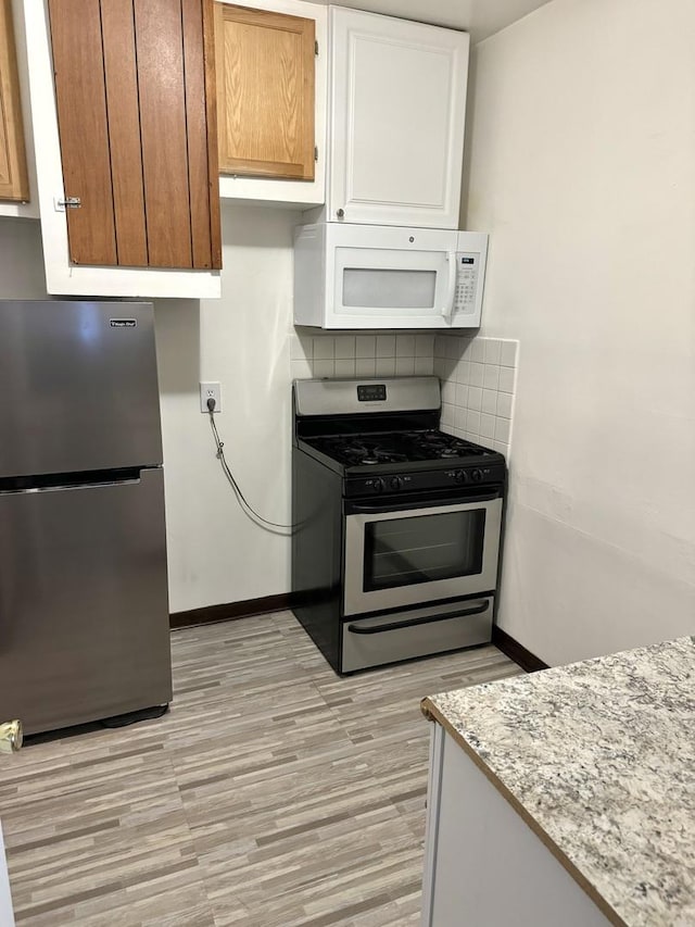 kitchen featuring stainless steel appliances, baseboards, white cabinets, decorative backsplash, and brown cabinetry