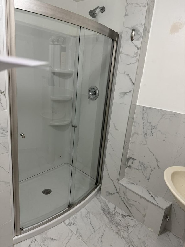 bathroom featuring a stall shower, marble finish floor, and tile walls