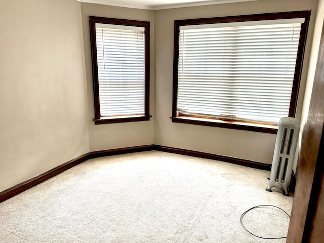 spare room with light carpet, baseboards, and radiator