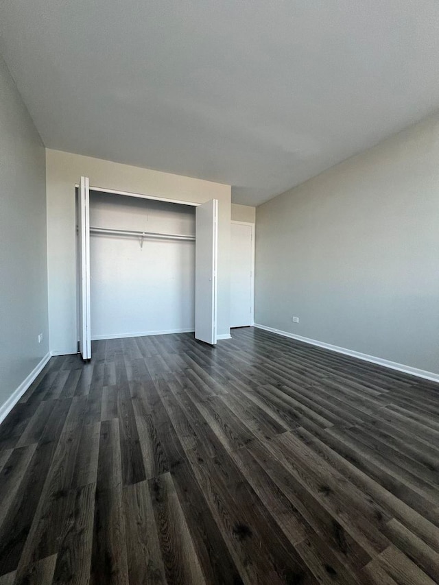 unfurnished bedroom featuring a closet and dark hardwood / wood-style flooring