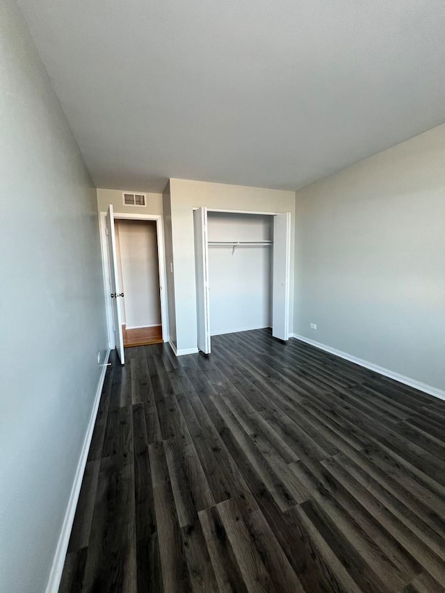 unfurnished bedroom with a closet and dark hardwood / wood-style flooring