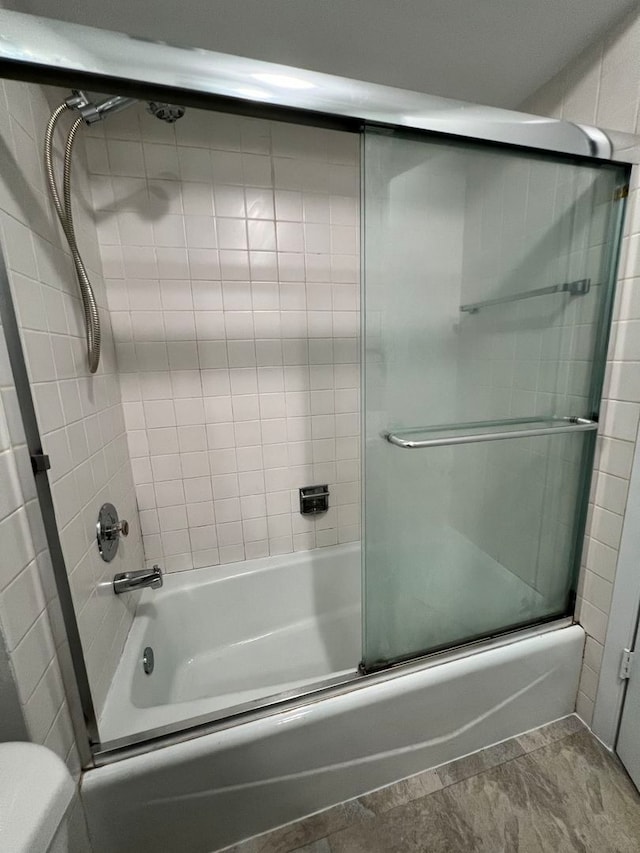 bathroom with toilet, bath / shower combo with glass door, and tile patterned floors