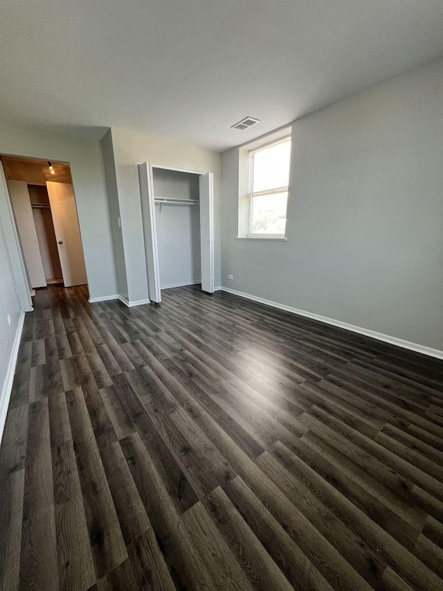 unfurnished bedroom with dark wood-type flooring, visible vents, and baseboards