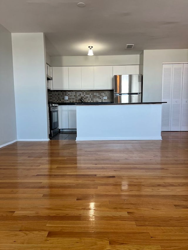 kitchen with white cabinets, stainless steel refrigerator, stove, and light wood-type flooring