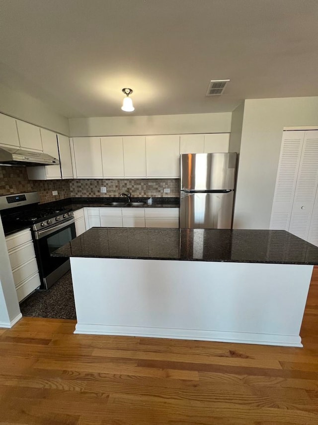 kitchen featuring appliances with stainless steel finishes, dark hardwood / wood-style flooring, backsplash, and white cabinets