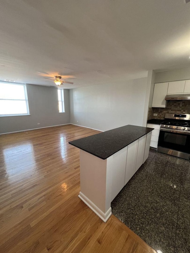 kitchen with dark countertops, modern cabinets, stainless steel range with gas stovetop, white cabinetry, and wood finished floors