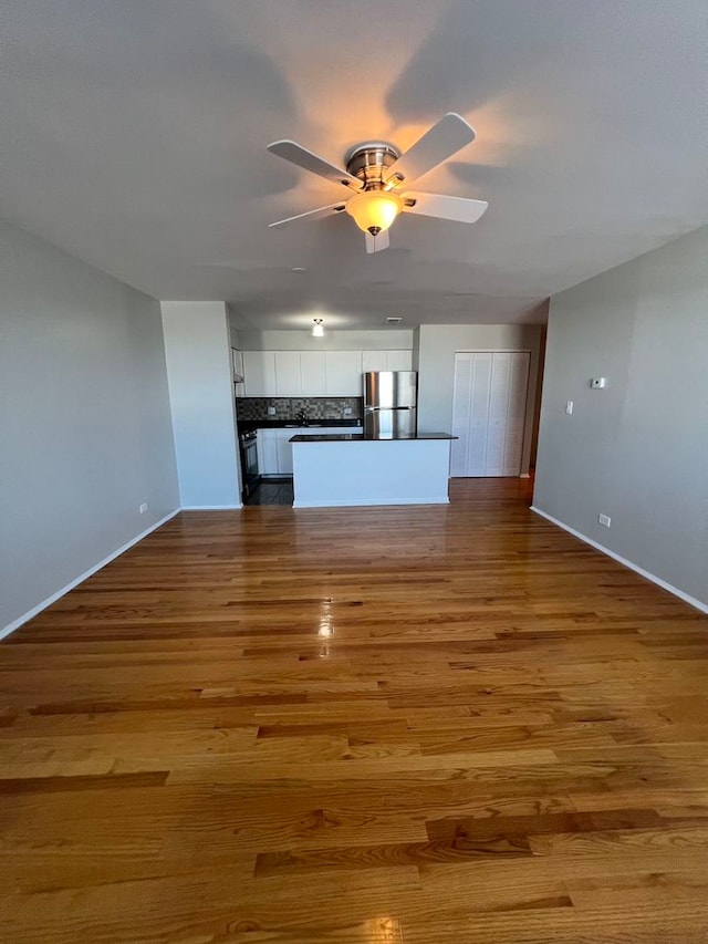 unfurnished living room featuring ceiling fan and hardwood / wood-style floors