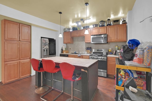 kitchen featuring a kitchen island, tile countertops, appliances with stainless steel finishes, dark wood-type flooring, and decorative backsplash