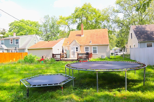 rear view of house with a wooden deck and a trampoline