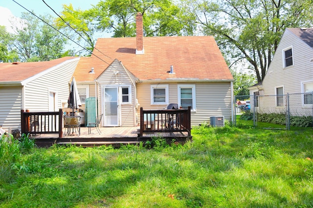 back of house featuring central air condition unit, a deck, and a lawn