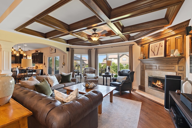 living room with beam ceiling, ornamental molding, coffered ceiling, dark wood-type flooring, and ceiling fan