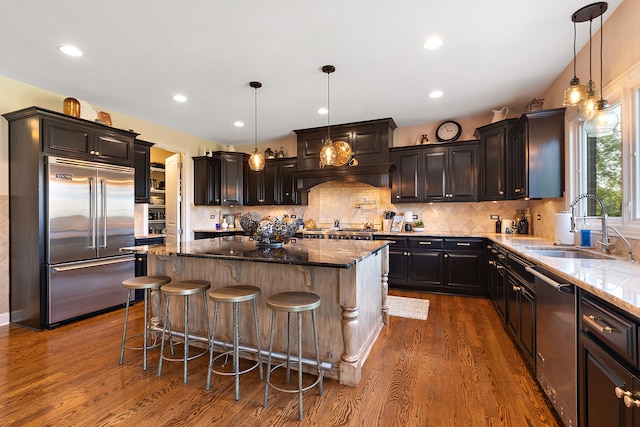 kitchen featuring stainless steel appliances, dark hardwood / wood-style floors, and dark stone counters