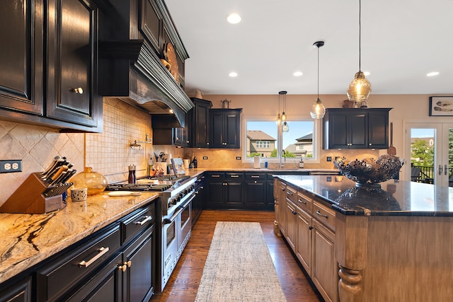 kitchen featuring decorative backsplash, dark wood-type flooring, range with two ovens, light stone counters, and a center island