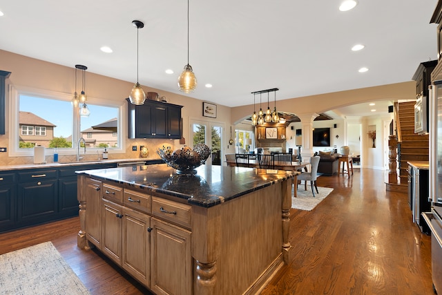 kitchen featuring a kitchen island, dark hardwood / wood-style flooring, sink, dark stone countertops, and decorative light fixtures