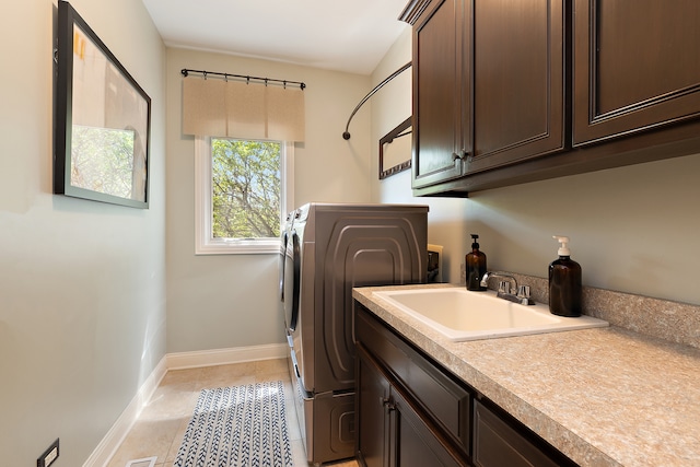 washroom with light tile patterned floors, sink, washing machine and dryer, and cabinets