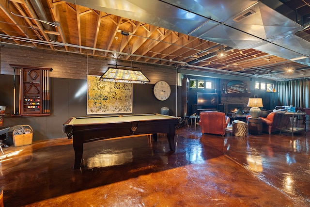 playroom with billiards, concrete flooring, and a stone fireplace