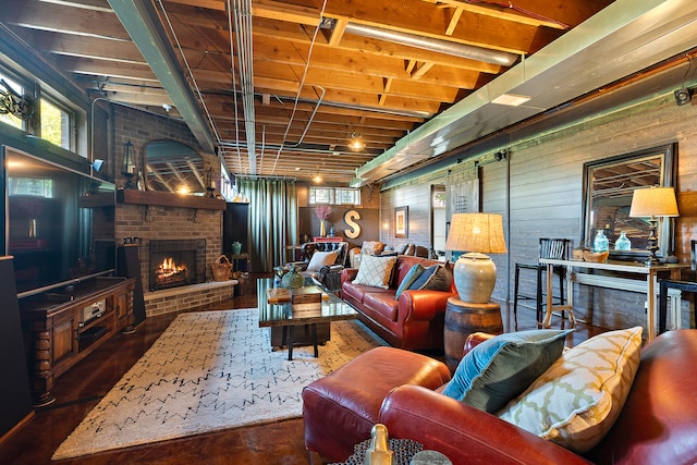 living room with wood walls, dark wood-type flooring, and a brick fireplace