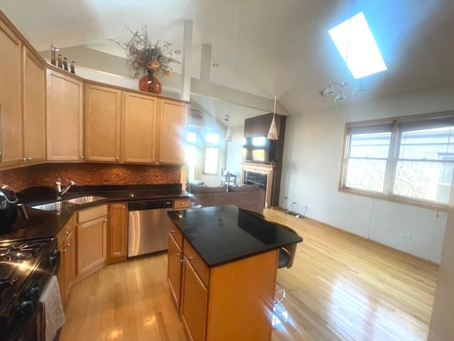 kitchen featuring a kitchen island, plenty of natural light, light hardwood / wood-style floors, stainless steel appliances, and vaulted ceiling with skylight