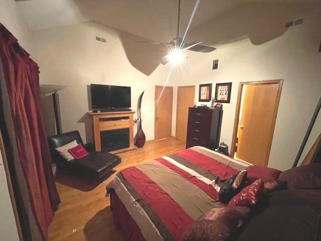 bedroom with vaulted ceiling, a fireplace, light wood-type flooring, and ceiling fan