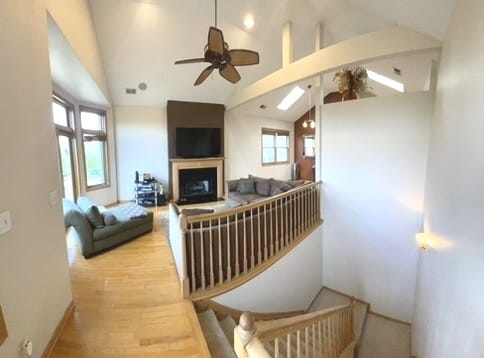 living room with ceiling fan, high vaulted ceiling, and light hardwood / wood-style flooring