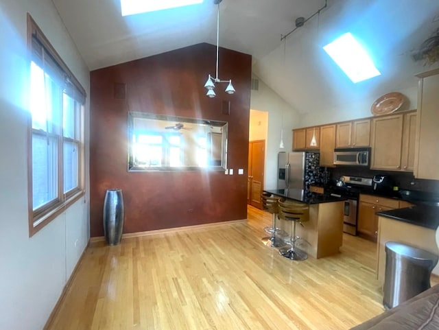 kitchen with a healthy amount of sunlight, a breakfast bar area, appliances with stainless steel finishes, a kitchen island, and light hardwood / wood-style floors