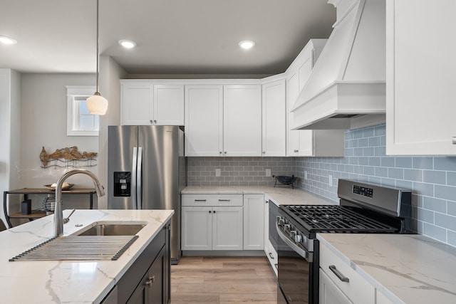 kitchen featuring light hardwood / wood-style floors, decorative backsplash, light stone counters, custom exhaust hood, and stainless steel gas range oven