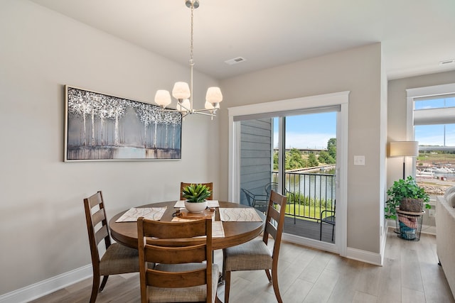 dining room with light hardwood / wood-style flooring and an inviting chandelier