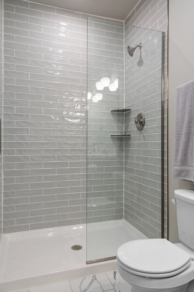 bathroom with tile patterned floors, toilet, and a tile shower