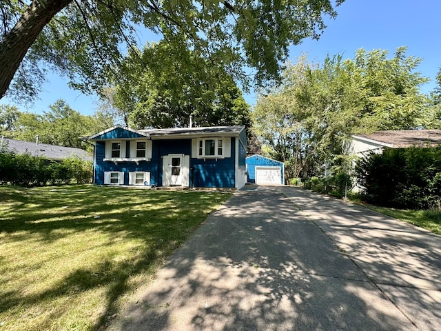 raised ranch with a garage, a front lawn, and an outbuilding