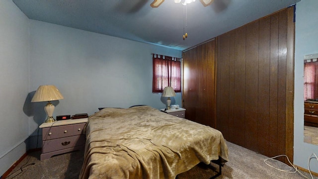 bedroom with carpet, ceiling fan, and wooden walls