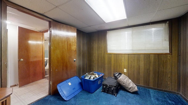 miscellaneous room featuring tile patterned flooring, wood walls, and a drop ceiling