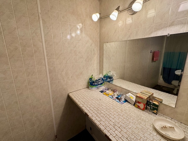 bathroom featuring vanity and tile walls