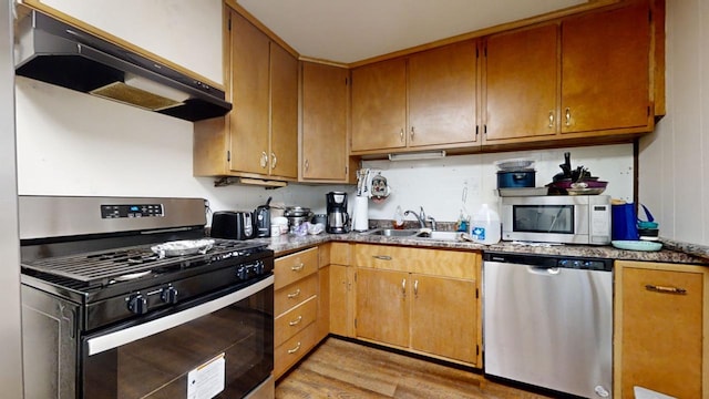 kitchen featuring appliances with stainless steel finishes, light hardwood / wood-style flooring, sink, and extractor fan