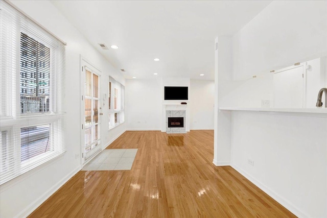 unfurnished living room with a premium fireplace and light wood-type flooring