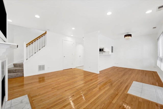 unfurnished living room with light hardwood / wood-style flooring and a chandelier