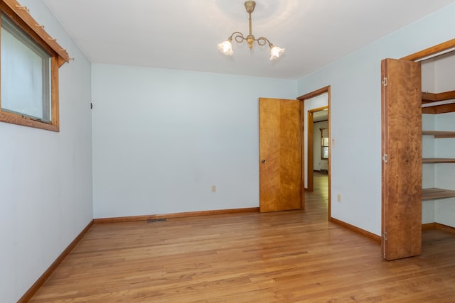 unfurnished bedroom featuring a notable chandelier and light hardwood / wood-style floors