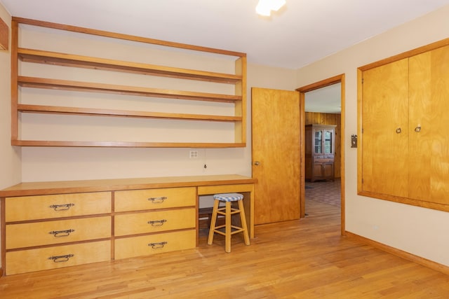 unfurnished office with light wood-type flooring and built in desk