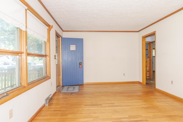 foyer entrance featuring a textured ceiling, ornamental molding, and light hardwood / wood-style floors