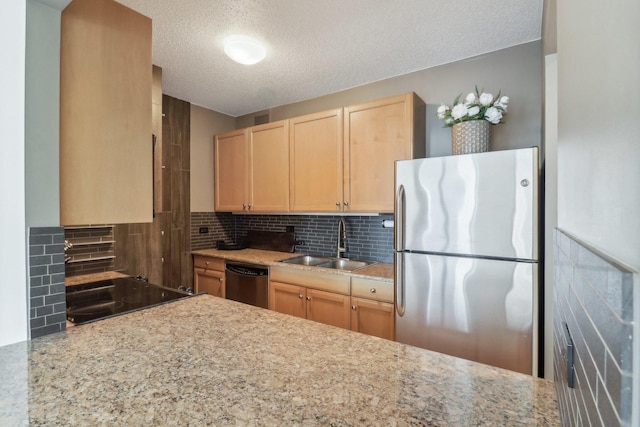 kitchen featuring light brown cabinets, decorative backsplash, appliances with stainless steel finishes, a textured ceiling, and a sink