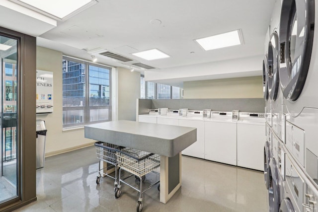 community laundry room with light tile patterned floors, baseboards, and stacked washer / dryer