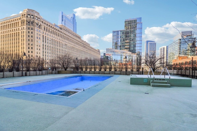 view of swimming pool with a view of city and fence