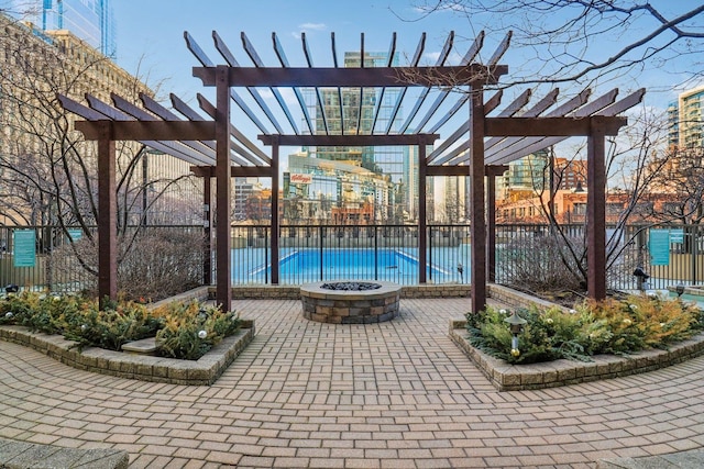 view of swimming pool featuring a pergola, an outdoor fire pit, a patio, and fence